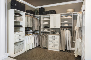Walk-in closet with white shelving and drawers that are filled with clothes